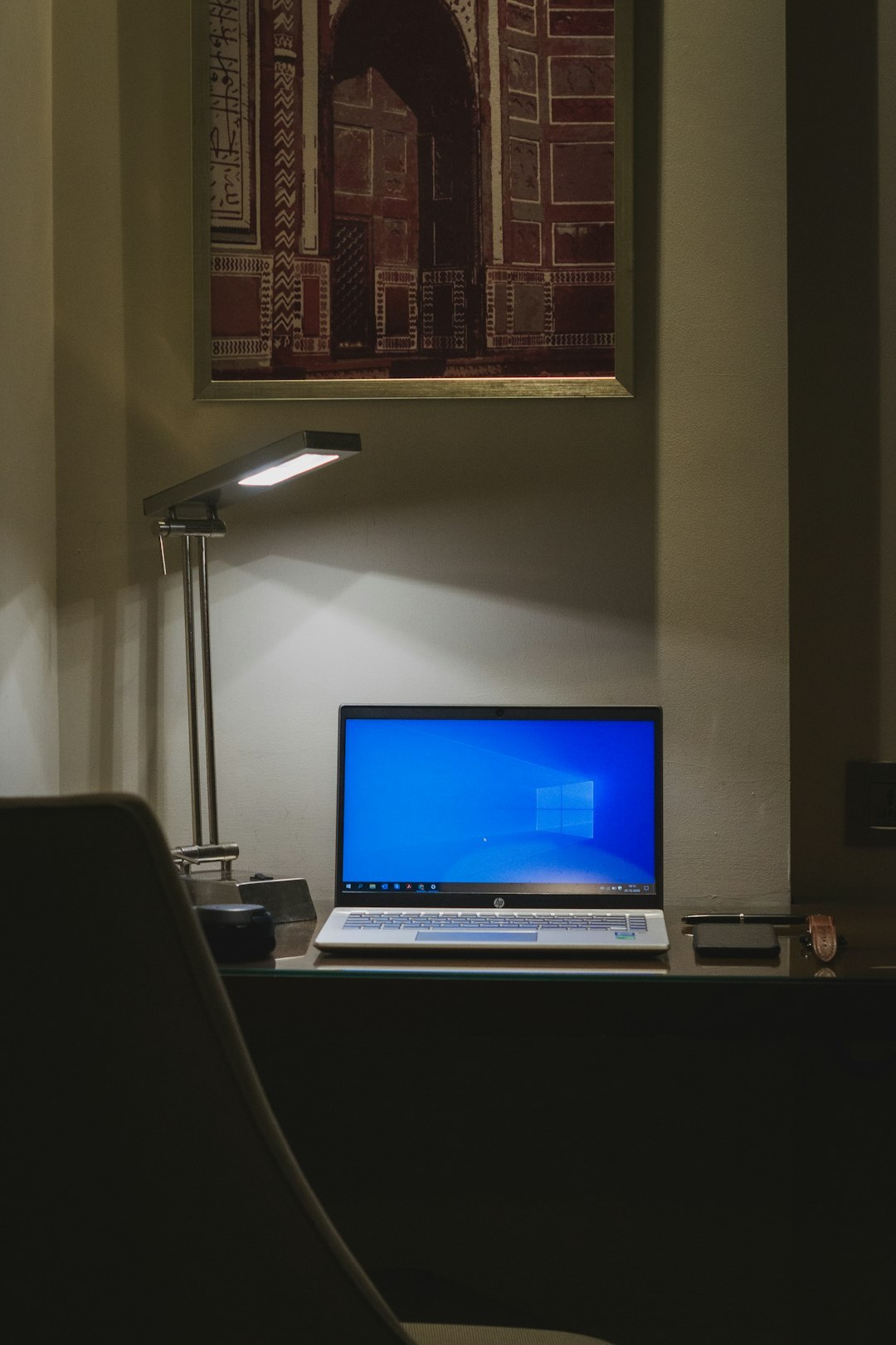 Close-up of a modern desk with laptop, notebook and desk lamp