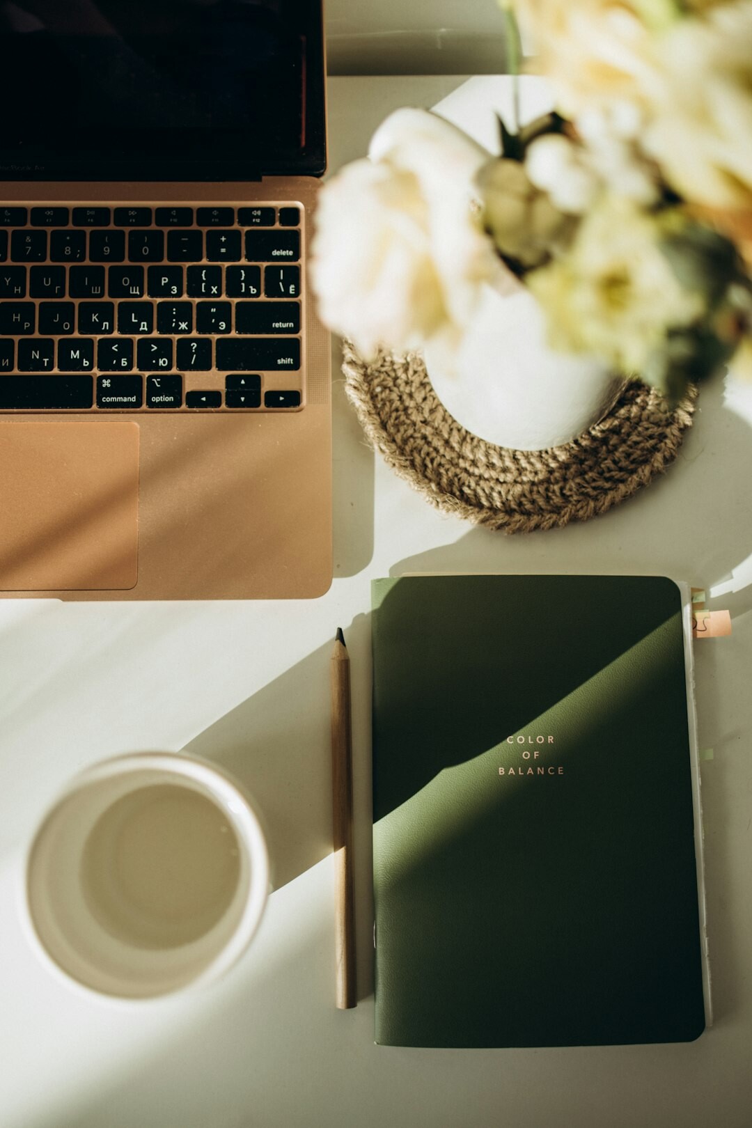 Top-down view of a desk with laptop, coffee cup and notebook
